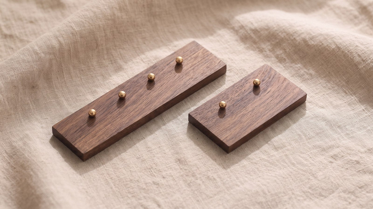 Pearl, gold disc and gemstone stud earrings pushed through the holes of a four-hole and a two-hole walnut earring board, butterfly backs visible underneath