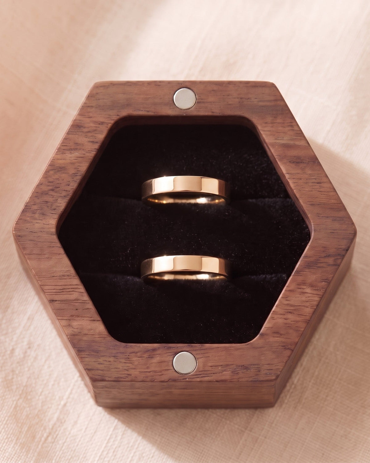 Walnut hexagon ring box with black velvet insert and two gold rings