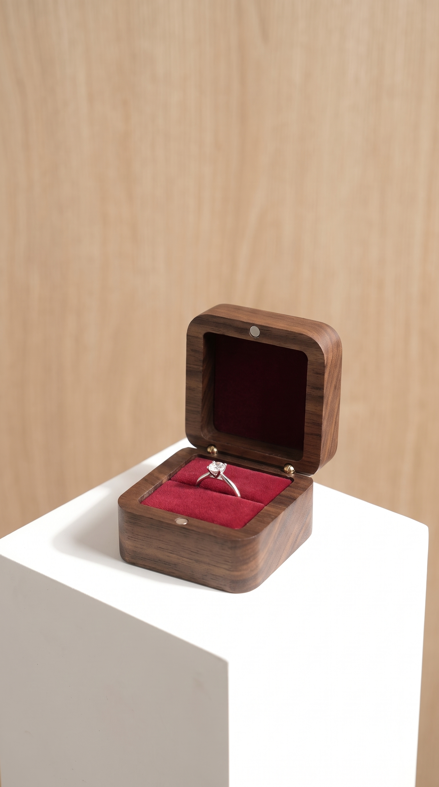 Walnut wood ring box with open lid and wine red velvet insert holding a ring