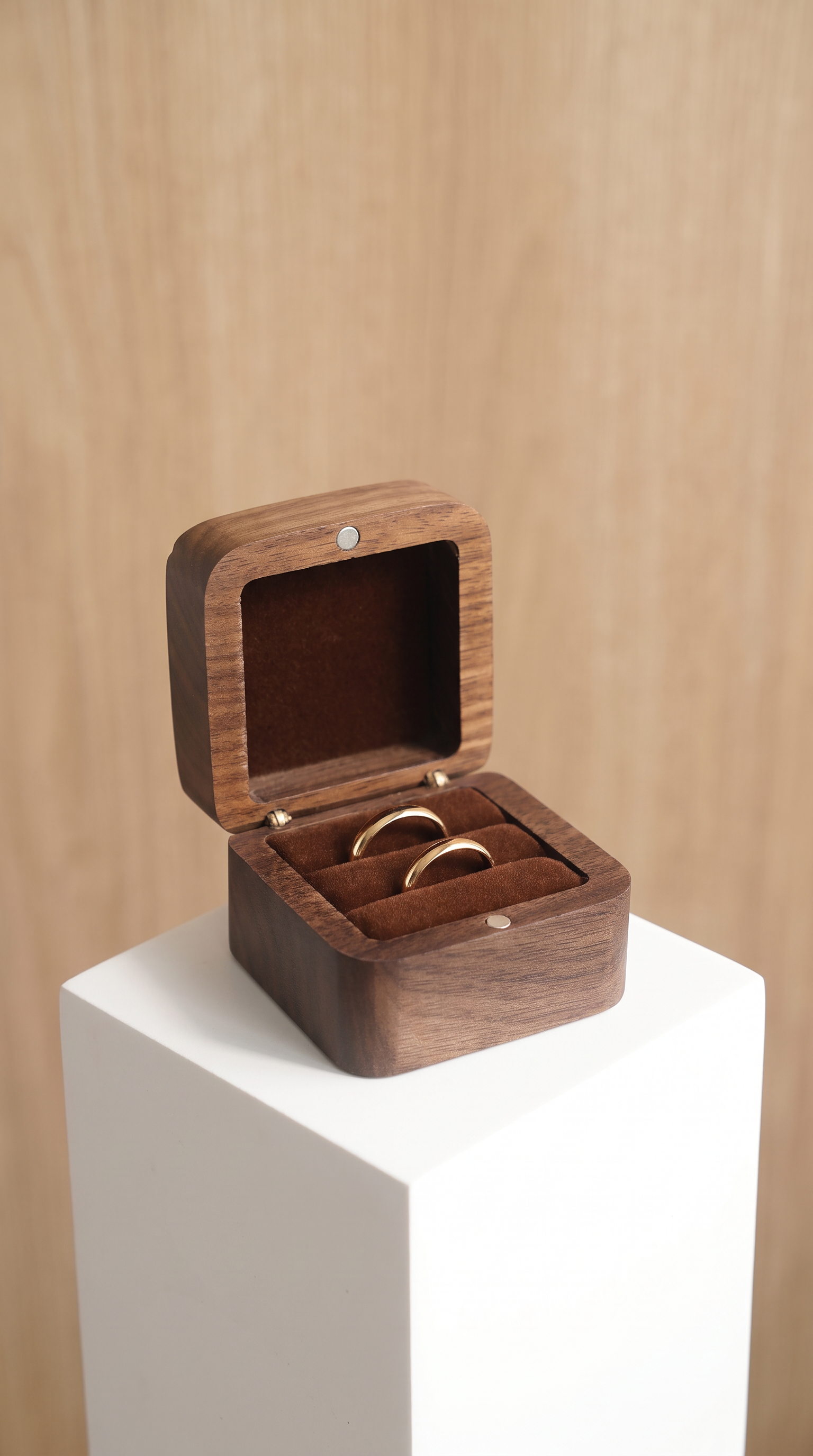 Walnut wood ring box with open lid and dark coffee velvet cushion holding two rings