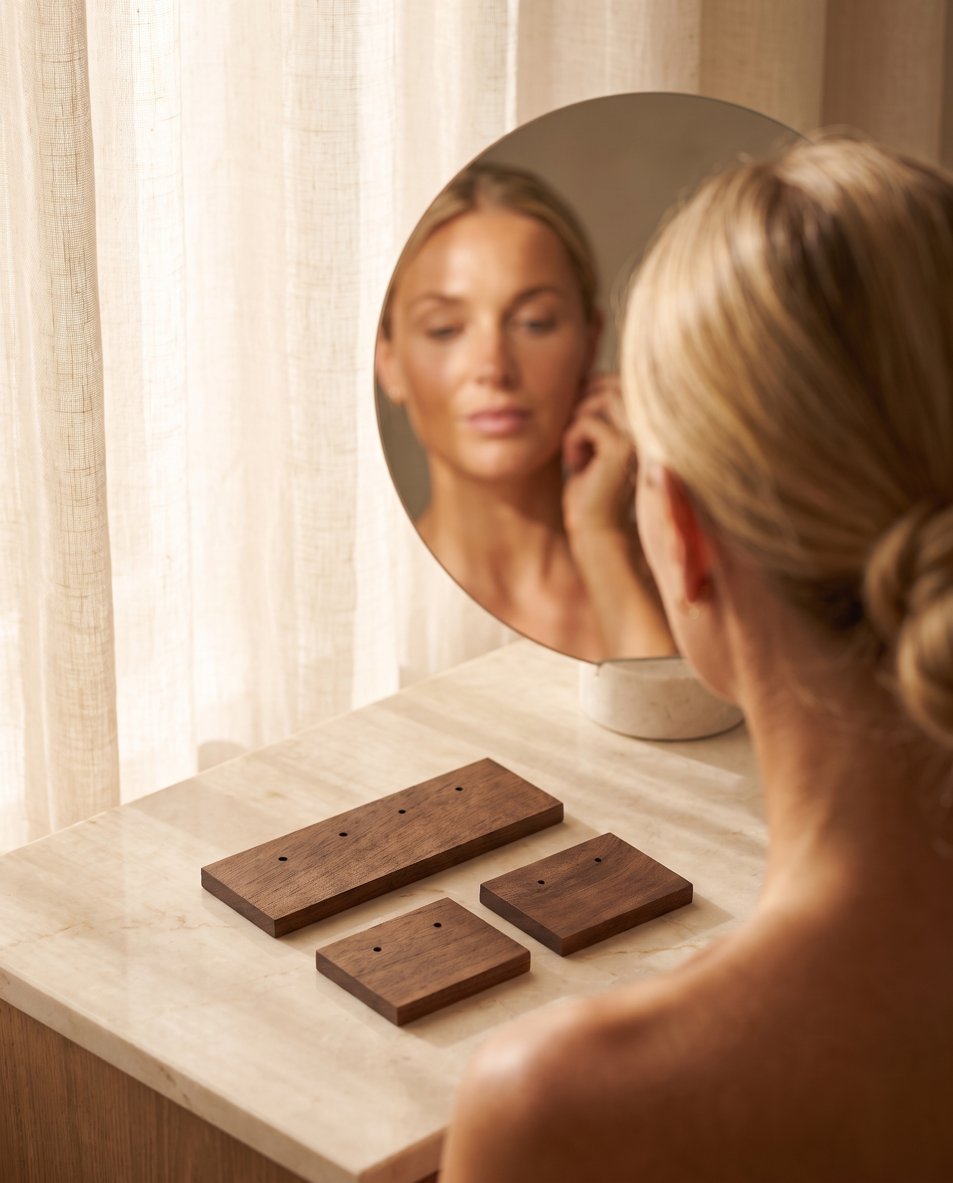Walnut earring holder boards on a tabletop, dark wood with multiple earring holes