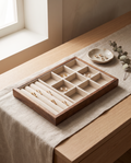 Walnut jewelry tray with velvet compartments holding rings and small earrings