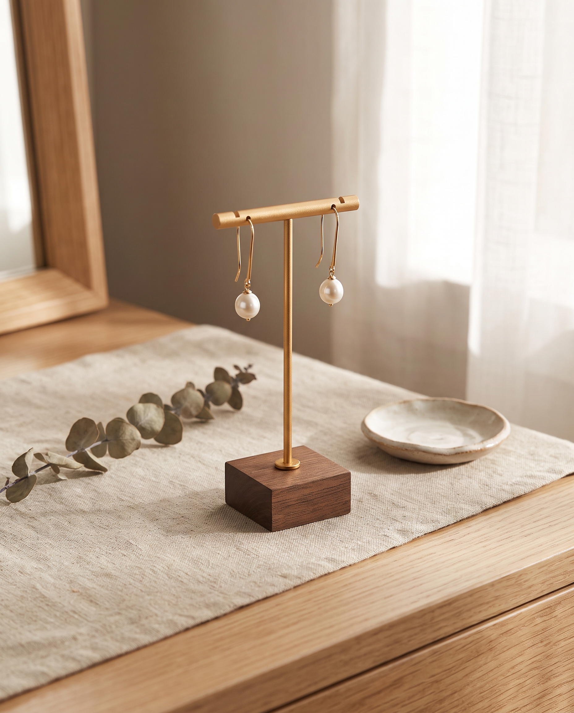 Gold T-bar earring stand with walnut base and two hanging pearl earrings