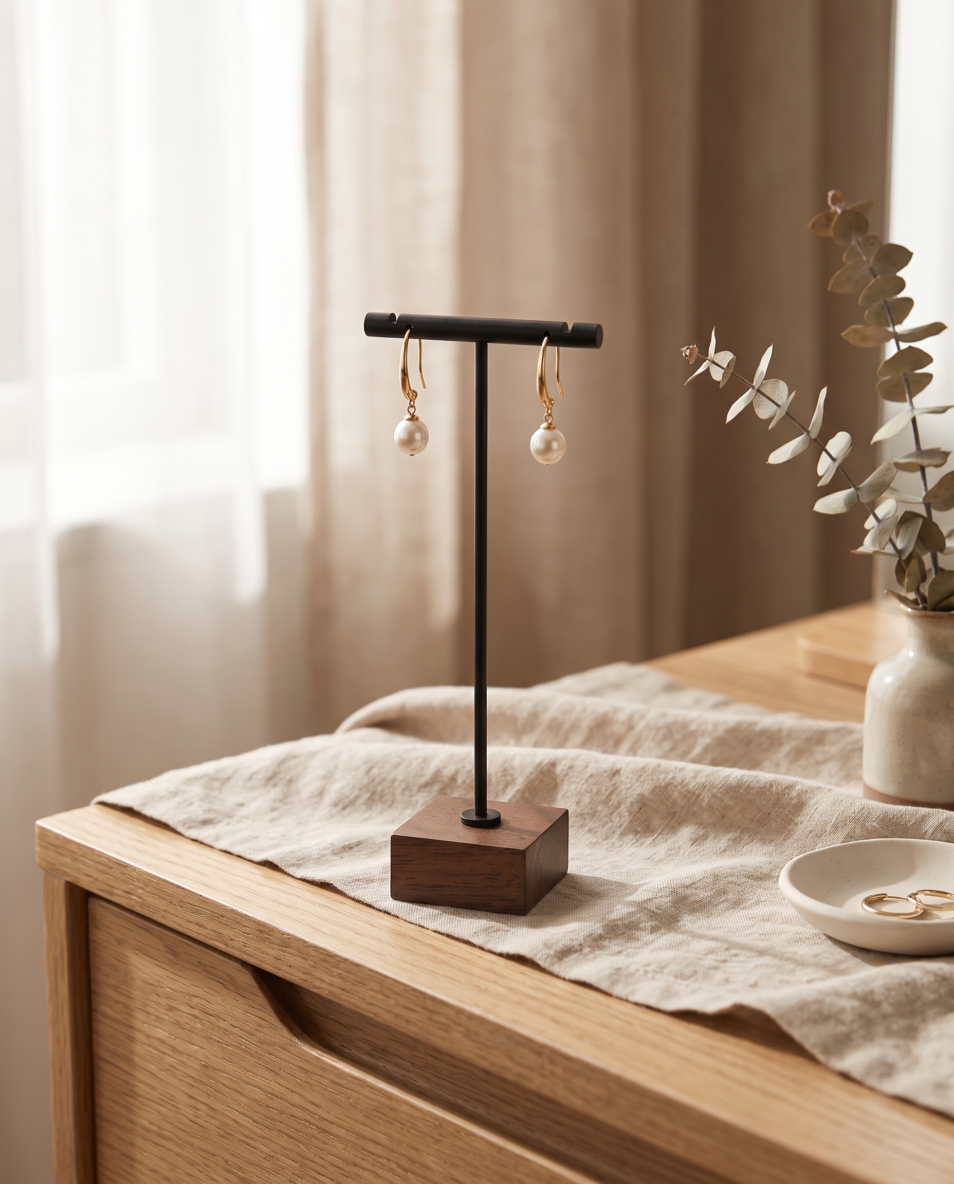 Matte black T-bar earring stand with walnut base and two dangling pearl earrings