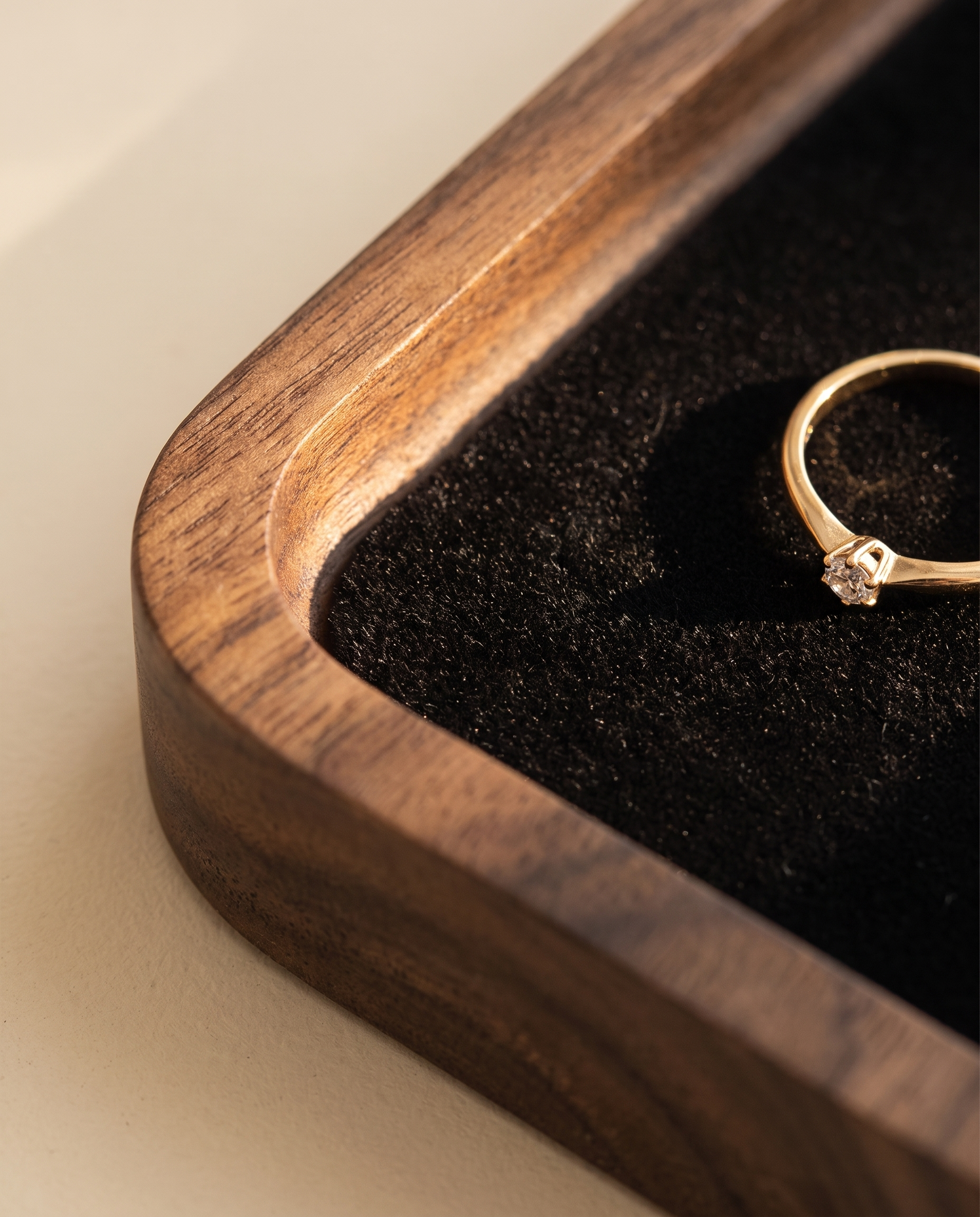 Walnut jewelry tray corner with black velvet lining and gold ring on inset