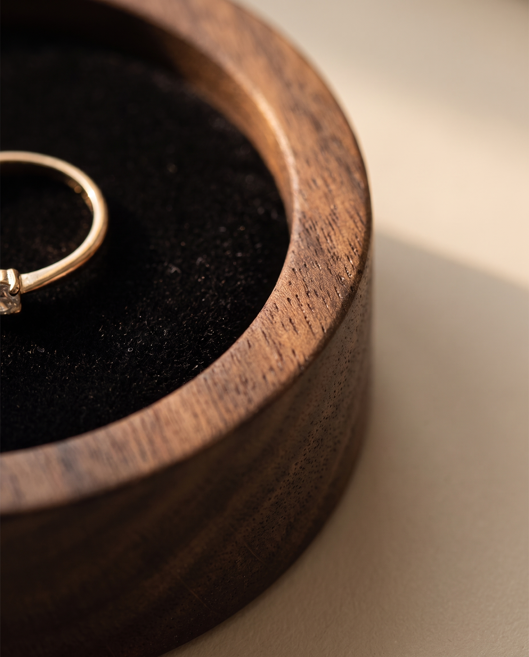 Close-up of small round walnut ring dish with dark velvet-lined center