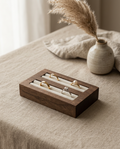 Walnut ring display tray with velvet channels, holding several rings