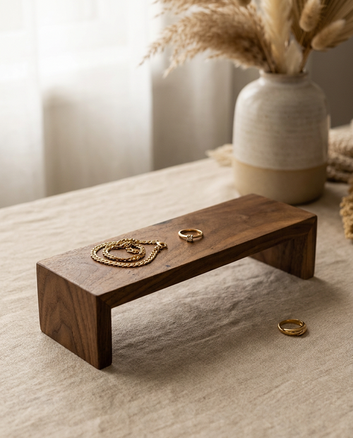 Walnut wood jewelry display riser stand with curved top and rings on it
