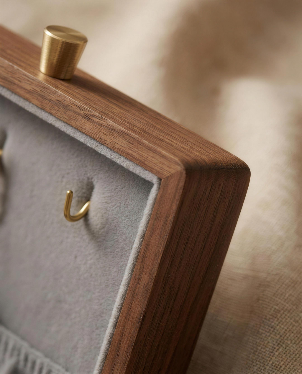 Walnut jewelry box corner with gray velvet lining and gold necklace hook