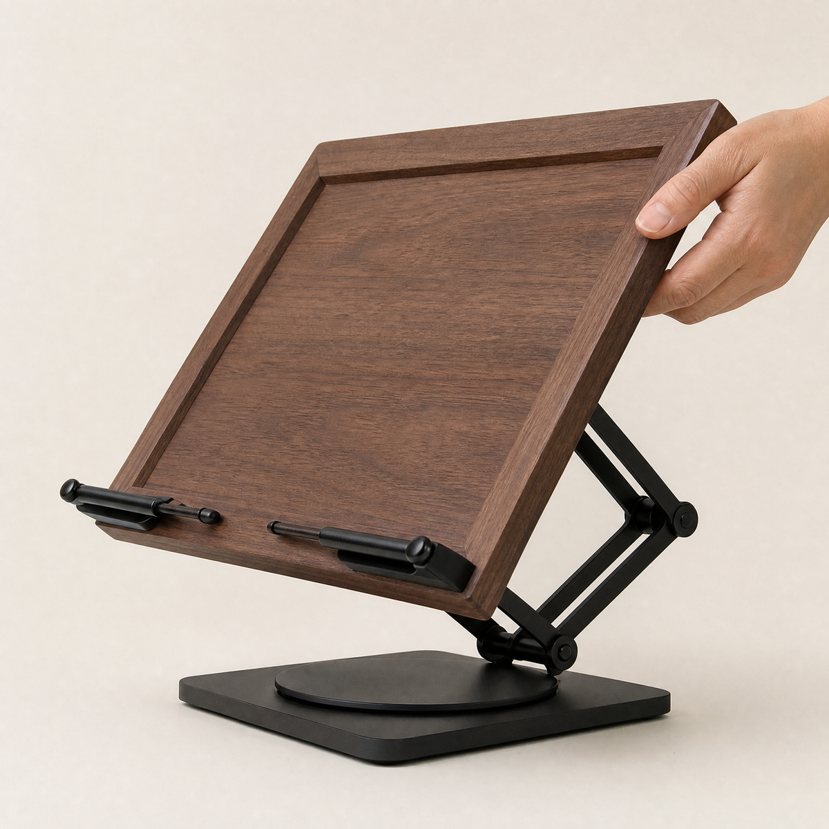 Adjustable walnut book stand with rotating base, viewed from the back; hand grips frame.