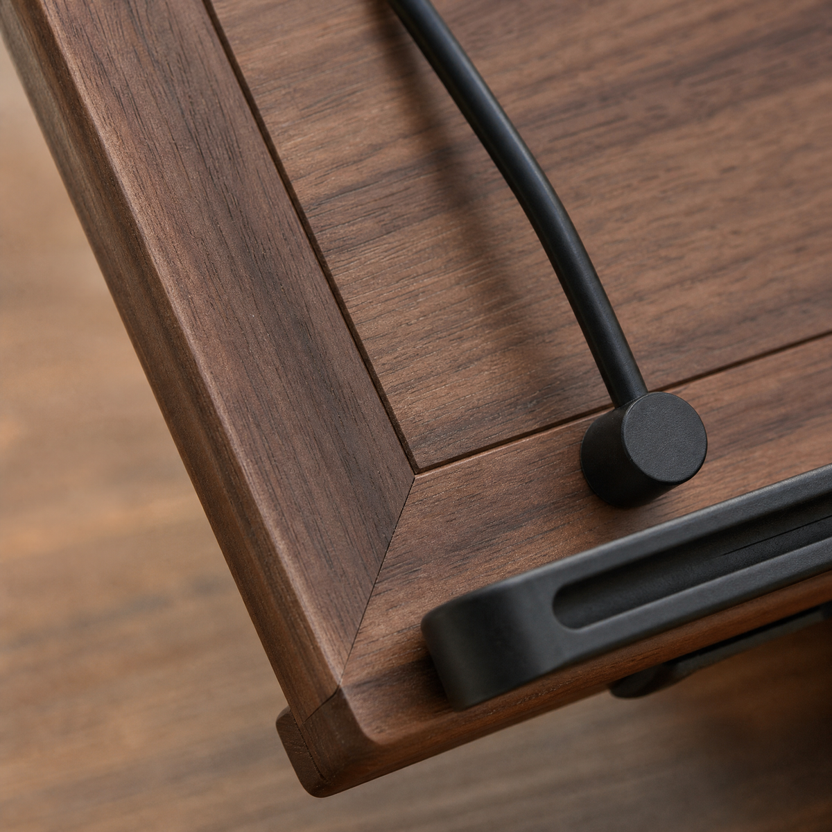 Close-up of walnut book stand brace and black support bar on the rotating base.