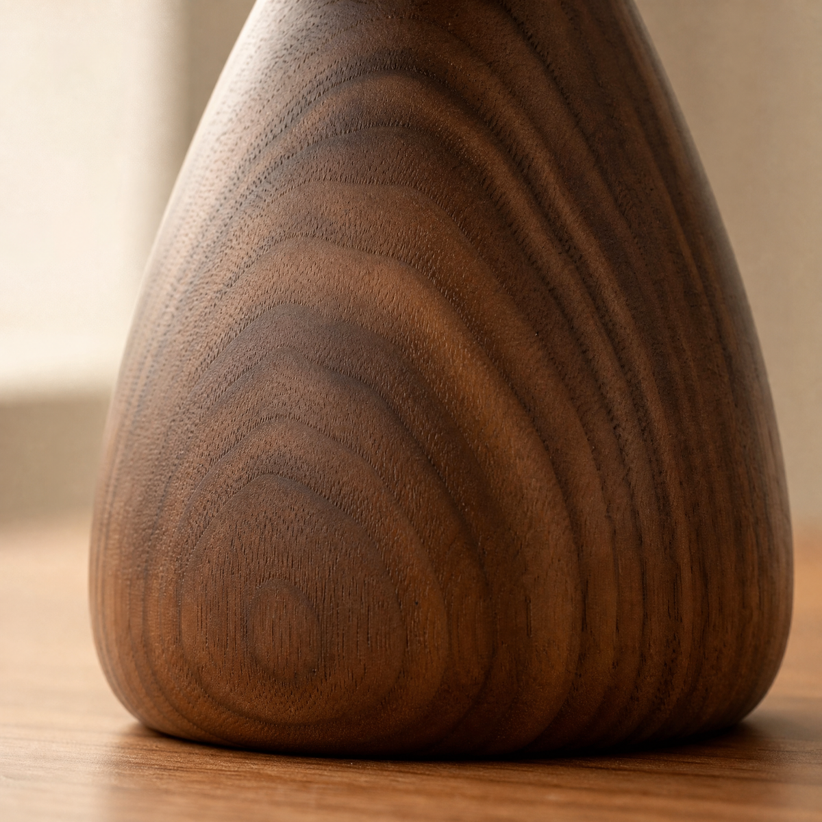 Walnut phone stand with smooth teardrop base and visible wood grain texture