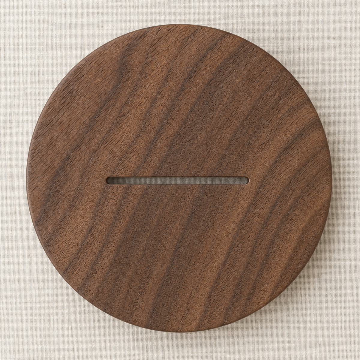 Single round walnut trivet with slim rectangular grip slot, dark wood grain.