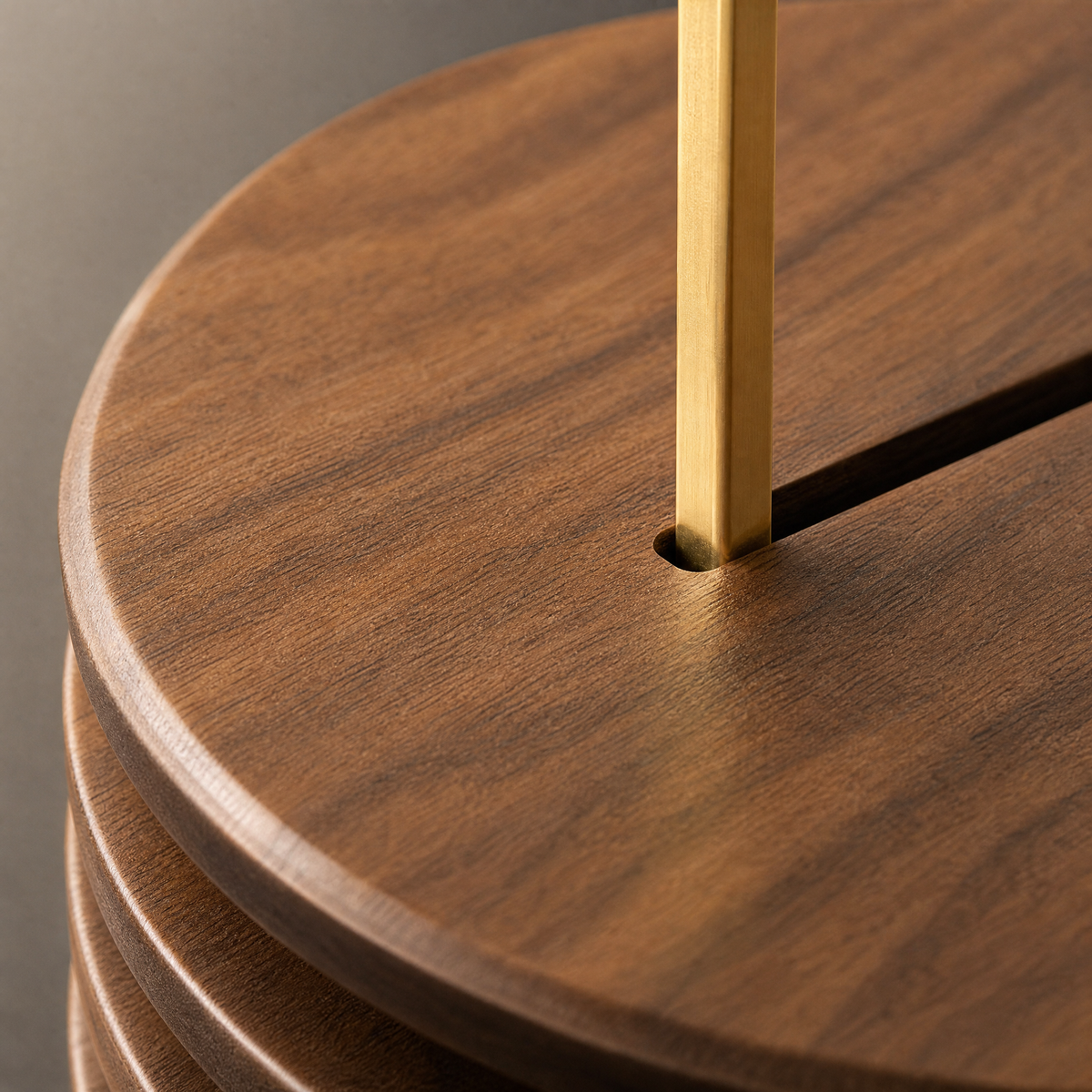 Close-up of round walnut trivet surface with brass handle attached.