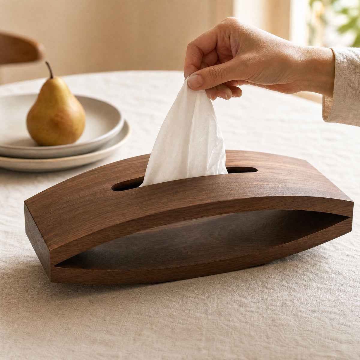 A tissue being drawn from the walnut cover at a dining table